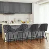 A kitchen or dining area with bar stools in the foreground and cabinets and a countertop in the background. Produktbild-Vorschau