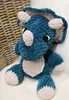 A plush triceratops toy is sitting on a white surface, with a wicker basket in the background. Náhľad obrázku produktu