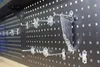 A pegboard wall with various hooks and a set of wrenches hanging on one of the hooks. Produktbild-Vorschau
