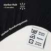 A close-up of a black fitted sheet with text and care symbols. Produktbild-Vorschau
