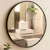 A round mirror reflecting a bathroom counter with toiletries and a plant. Produktbild-Vorschau