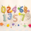 Farbenfrohe Geburtstagsdekoration mit schwebenden Folienballons in Form der Zahlen 0 bis 9 in Pastellfarben, jeweils mit niedlichen Gesichtern und Partyhütchen. Anteprima dell’immagine prodotto