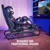 A person in racing gear sits in a racing simulator cockpit, playing a racing game on a large screen. Produktbild-Vorschau
