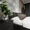 A close-up view of a bed in a bedroom, with a nightstand and flowers in the foreground. Produktbild-Vorschau