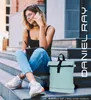 A young woman sits on steps, talking on her phone and holding a tablet, with a mint green backpack beside her. Produktbild-Vorschau