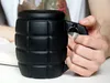A person's hand is holding a black grenade-shaped coffee mug. Voir les images du produit