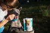 A woman is feeding a dog a treat from a bag of GELOREN dog supplement. Produktbild-Vorschau
