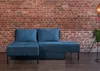 A blue sectional sofa is placed against a brick wall. Produktbild-Vorschau