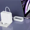 A white laptop charger is plugged into a wall socket and connected to a laptop. Produktbild-Vorschau