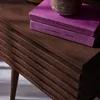A close-up view of a wooden nightstand with two purple books on top. Produktbild-Vorschau