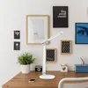 A desk with a lamp, plant, camera, and framed pictures on the wall. Podgląd zdjęcia produktu