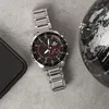 A watch is placed on a textured gray surface next to a globe and a smartphone. Náhled obrázku produktu