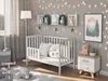 A nursery room with a baby crib, a nightstand, and decorative elements. Anteprima dell’immagine prodotto