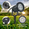 A black LED garden spotlight with a ground stake, shown in a grassy outdoor setting with a sunset in the background. Close-up insets highlight construction details and the LED lights. Produktbild-Vorschau