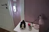 A bedside table with a stuffed dog, a small vase with a rose, and a pink desk lamp. Produktbild-Vorschau