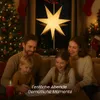A family is gathered around a table, drawing and spending time together during Christmas. A large star decoration hangs in the window behind them, and a Christmas tree is visible on the left. Podgląd zdjęcia produktu