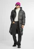 A man wearing a black puffer coat, white turtleneck, and pink beanie stands against a white background. Voir les images du produit