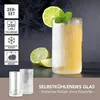 A close-up of a self-cooling glass filled with a yellow beverage, garnished with lime and mint, with two empty glasses in the foreground. Voir les images du produit
