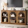 A wooden console table with arched compartments, styled with decorative items and a television above. Voir les images du produit