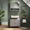 A modern bathroom with green tiled walls, a sink, vanity, and shelving unit. Voir les images du produit
