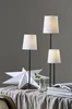 Three white lampshades on black stands, a white star decoration, and a vase with a plant on a table covered with a grey cloth. Podgląd zdjęcia produktu