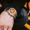 A close-up shot of a person's wrist wearing a silver and orange G-Shock watch. Produktbild-Vorschau