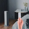 A hand holding a remote control in a bedroom setting. Voir les images du produit