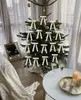 A decorated Christmas tree with beige bows and gold ornaments, set in a cozy indoor environment with a blanket and champagne glasses. Voir les images du produit
