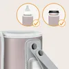 Close-up of a pink bottle warmer with two circular insets showing its use with a baby bottle and a coffee cup. Produktbild-Vorschau