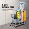A cleaning cart with various cleaning supplies, including mops, bottles, and a caution sign, is shown against a light-colored wall. Náhled obrázku produktu