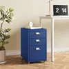 A blue metal filing cabinet with three drawers is placed next to a potted plant and a desk with a laptop and lamp. Voir les images du produit