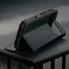 A black leather phone case with red stitching is shown standing upright on a dark surface. Produktbild-Vorschau