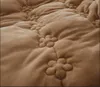 A close-up view of a textured brown blanket with a quilted floral pattern. Produktbild-Vorschau