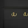 A close-up view of two gold hooks mounted on a black surface. Anteprima dell’immagine prodotto