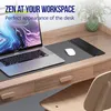 A laptop and mouse are placed on a desk mat on a wooden desk, with a plant in the background. Produktbild-Vorschau