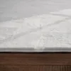 A close-up, low-angle view of a white shaggy rug on a wooden floor. Produktbild-Vorschau