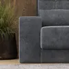 A close-up view of a gray sofa with a potted plant in the background. Náhled obrázku produktu
