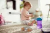 A baby is playing on the floor with toys, and a Philips Avent sippy cup is in the foreground. Voir les images du produit