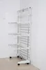 A white multi-tiered drying rack with wheels is positioned in the corner of a room with white tiled walls and a tiled floor. Produktbild-Vorschau