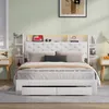 A white upholstered bed with a headboard featuring built-in shelves and LED lighting, set in a bedroom with bedside tables and artwork. Produktbild-Vorschau