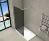A modern bathroom with a walk-in shower, towel rack, and a large window overlooking a tropical scene. Produktbild-Vorschau