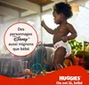 A baby wearing a diaper is standing and playing with a toy. There is text and a logo overlay. Náhľad obrázku produktu