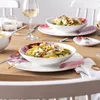 A table setting with plates of pasta and wine glasses. Voir les images du produit
