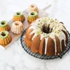 A large bundt cake and several mini bundt cakes are arranged on a marble surface and a wooden cutting board. Produktbild-Vorschau