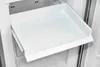 An empty white plastic drawer being pulled out of a refrigerator. Produktbild-Vorschau
