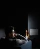A man relaxes with his feet up, looking towards a wall-mounted heater. Náhľad obrázku produktu