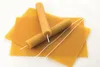 A close-up shot of beeswax candle making sheets and rolled beeswax candles with wicks. Náhled obrázku produktu