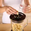 A person is adding a piece of chopped fruit to a blender filled with more fruit. Produktbild-Vorschau
