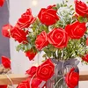 A string of red rose-shaped LED lights is draped around a vase of red roses and greenery. Produktbild-Vorschau