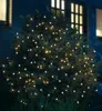 A bush decorated with warm white LED lights at night, with a house in the background. Produktbild-Vorschau